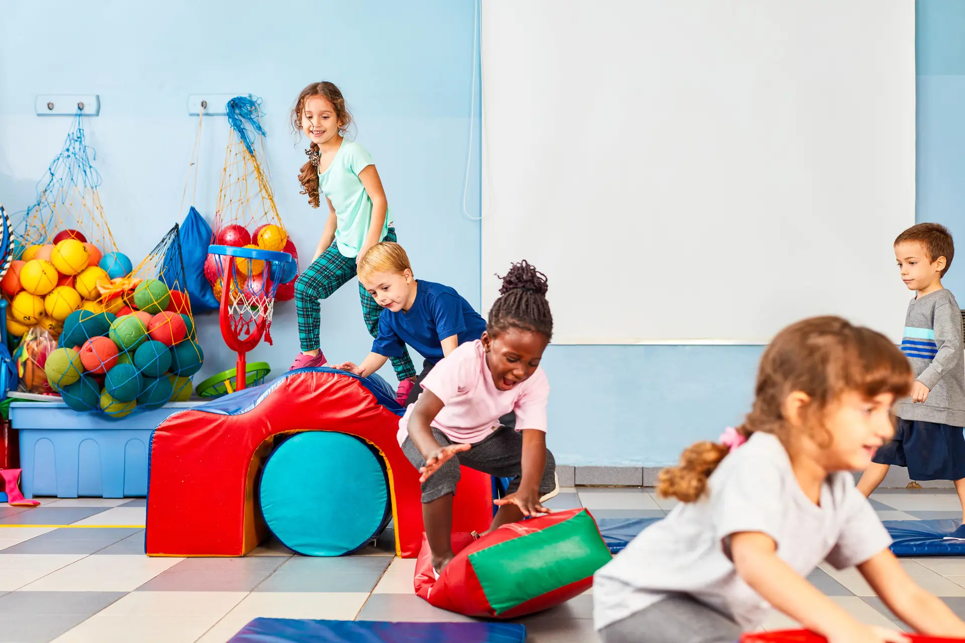 Kinder spielen fröhlich in der Turnhalle.