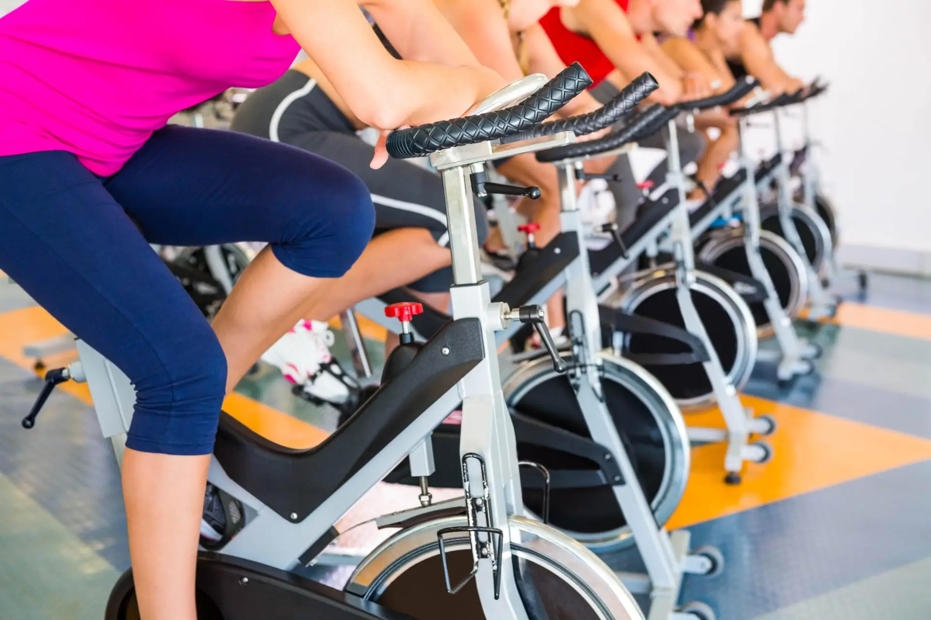 Mehrere Personen trainieren synchron in einem Spinning-Kurs.