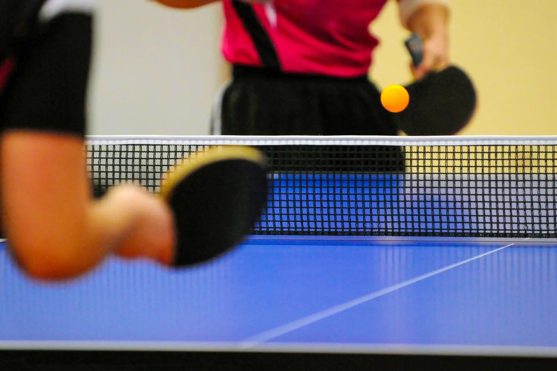 Tischtennisspieler*in beim Aufschlag in der Halle